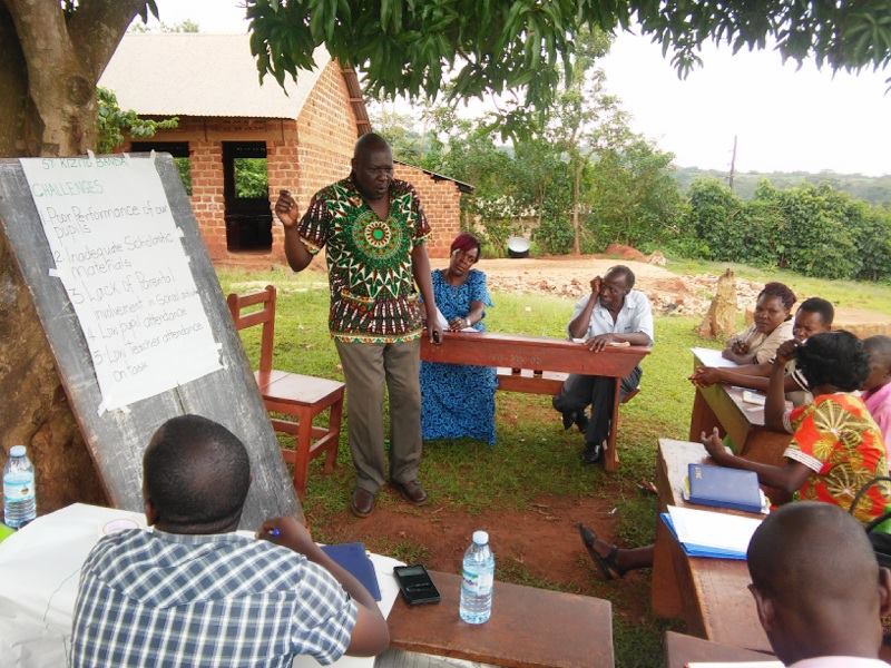 A teacher training session outdoors under a tree. 