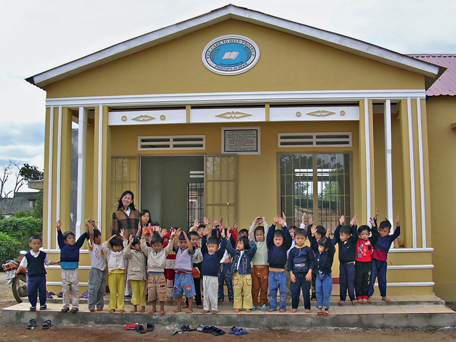A classroom of young children in front of the Friends school built by Care to Help. 